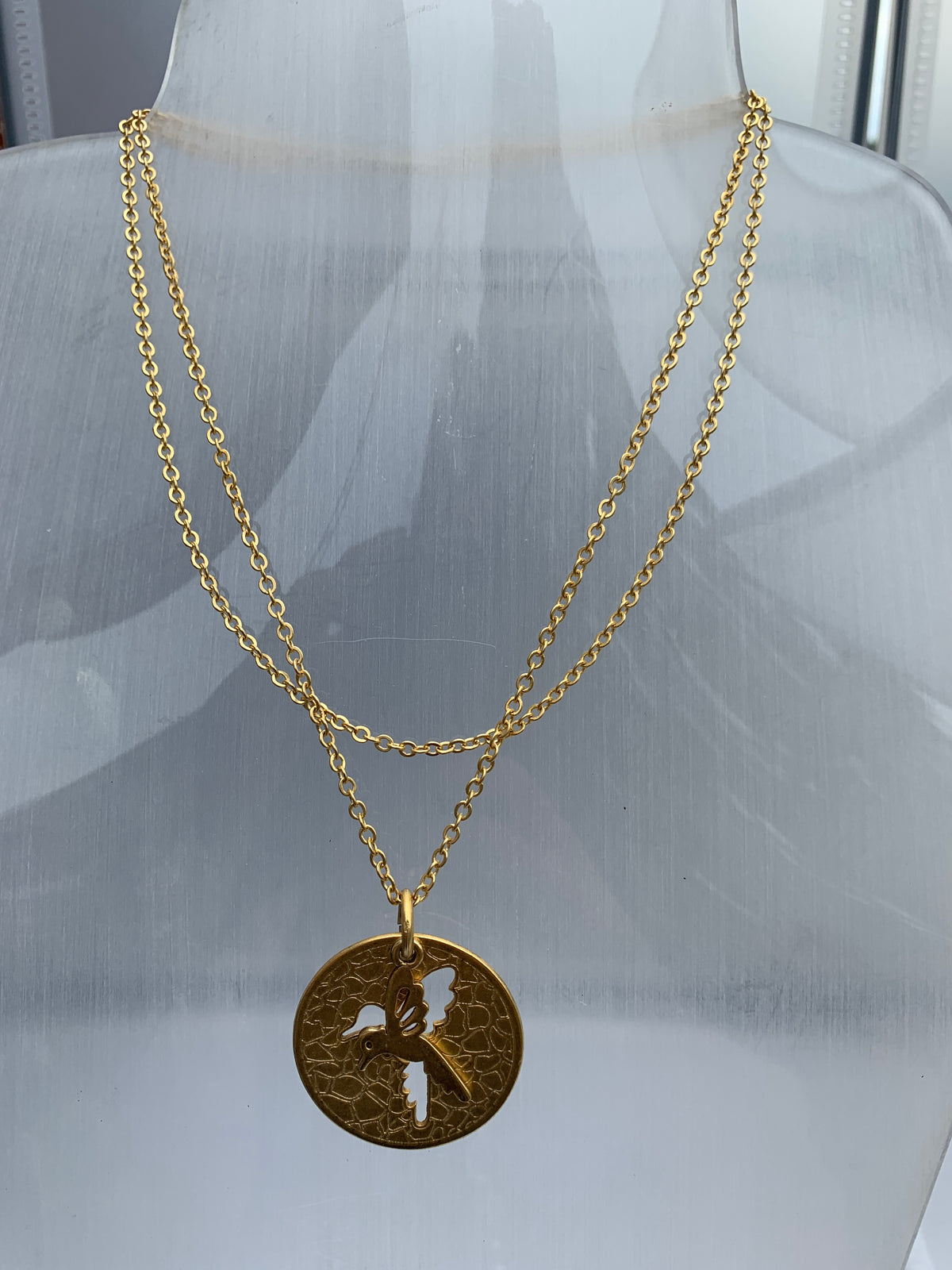Circular charm with bird cut out on a double chain