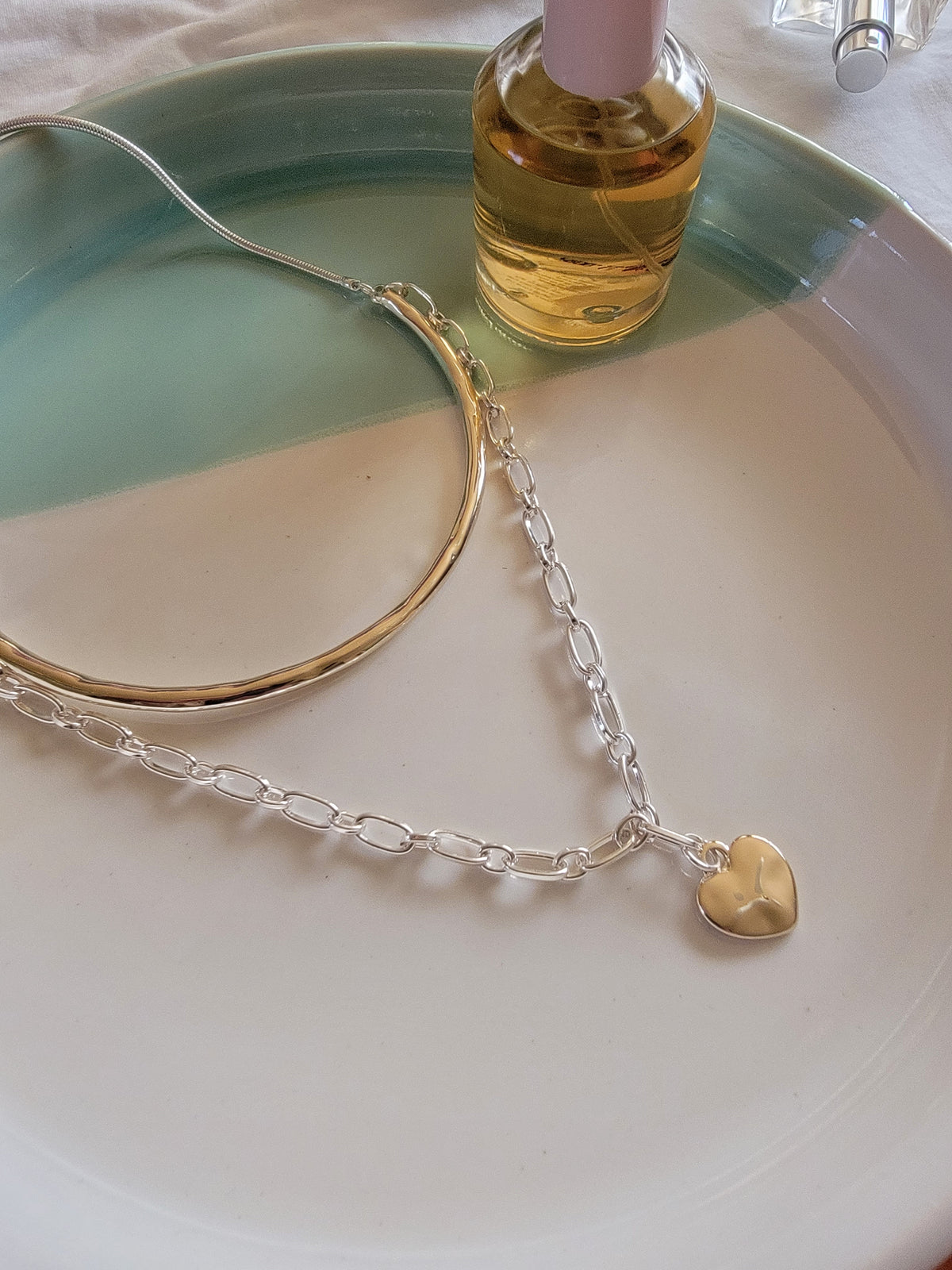 merx fashion chain  link heart necklace next to perfume bottle