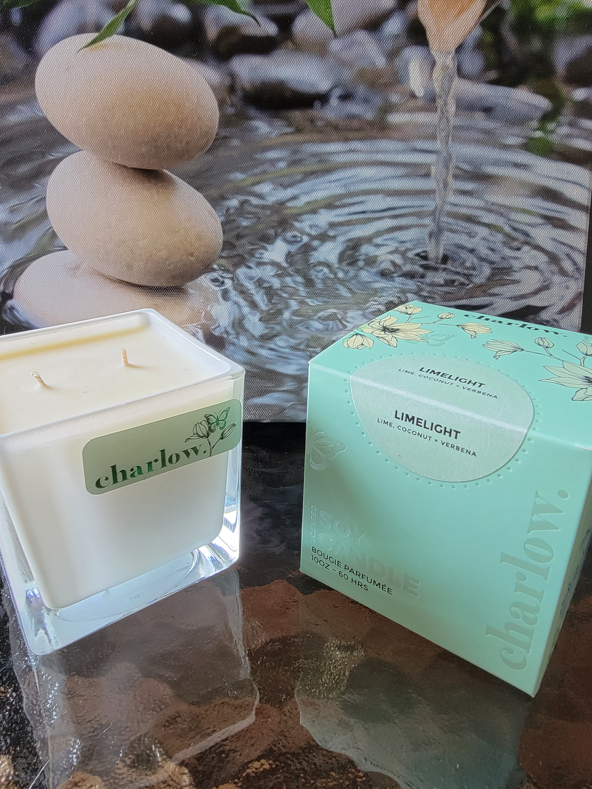 Charlston &amp; Harlow Limelight Candle on a table with flowing water and rocks in the background