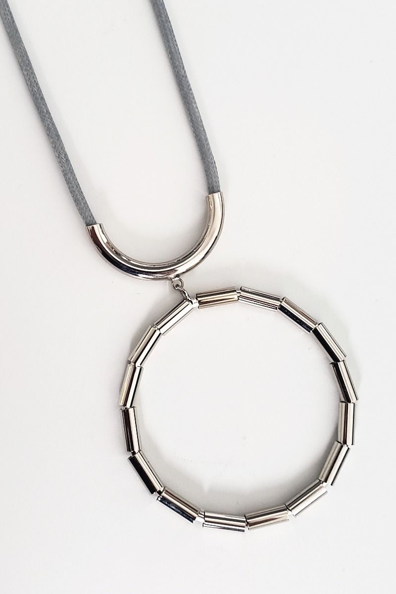 A fashion jewellery necklace that has a silver tone  circular pendant  on a cord that is convertible so it can be worn long or short.  18.5 &quot; 3&quot; decor drop